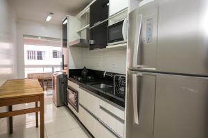 cocina con nevera de acero inoxidable y mesa en Apartamento AV. Brasil Frente Sh. Atlântico, en Balneário Camboriú