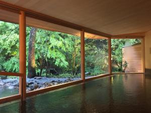 an indoor pool in a house with a view of the forest at Taishoya in Ureshino