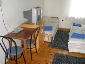 um quarto com uma mesa, uma televisão e uma cama em Fenyő Panzió em Makó