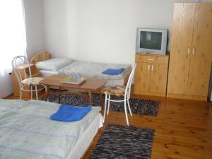 a room with a bed and a table and a tv at Fenyő Panzió in Makó