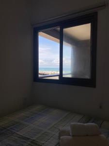 een slaapkamer met een raam met uitzicht op het strand bij AlahMar - Conforto na Praia in Salvador