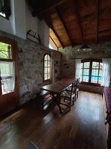 comedor con mesa de madera y algunas ventanas en Casa Soleares en Villa Las Rosas