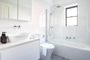 ein weißes Bad mit einem Waschbecken und einem WC in der Unterkunft Manly Cosy Retreat - Short walk to beach in Sydney