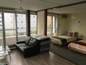 ein Wohnzimmer mit einem Sofa, einem Bett und Fenstern in der Unterkunft Compass in Nagano