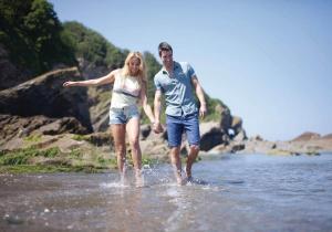 Ein Mann und eine Frau wandeln im Wasser in der Unterkunft Beach Cove Coastal Retreat in Ilfracombe