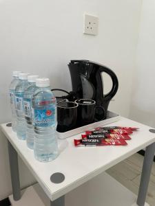 uma mesa branca com garrafas de água e um liquidificador em Casa Lena em Cherating