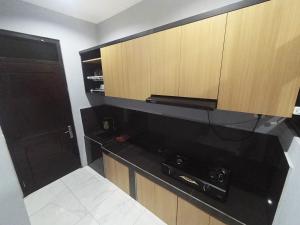 a kitchen with a black counter and wooden cabinets at Polkesyo Homestay Jogja in Sleman