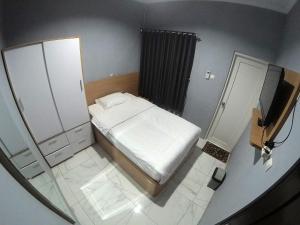 a small bedroom with a bed and a mirror at Polkesyo Homestay Jogja in Sleman