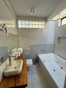 Un baño con bañera, inodoro y lavabo. en Cabana Toscana, en Campos do Jordão