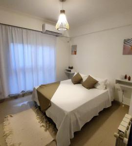 1 dormitorio con cama blanca y ventana en deanfunes home en Salta