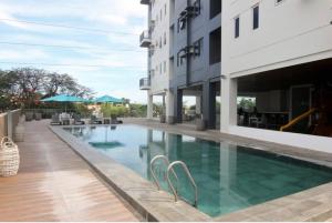a swimming pool with chairs next to a building at 1 bedroom condo unit at Sundance Residences in Cebu City