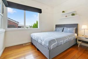 a bedroom with a bed and a large window at Hotham Heights in Warrnambool