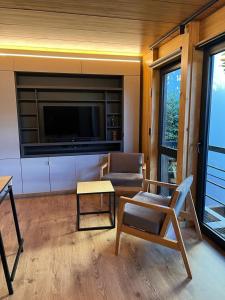 a living room with a tv and a chair and a table at VIVERO 5 UF15 in San Martín de los Andes