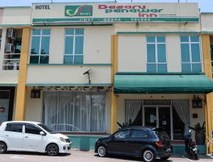 two cars parked in front of a building at Desaru Penawar Inn in Desaru