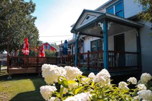 a house with a porch with white flowers in the yard at Maison Cadorette in Saint-Jean-des Piles