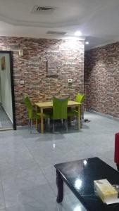 a dining room with green chairs and a brick wall at شقق رهف السالميه in Kuwait