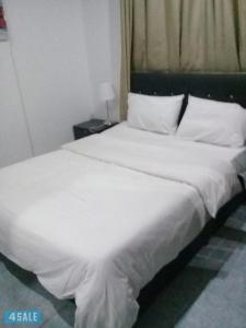 a bed with white sheets and pillows in a room at شقق رهف السالميه in Kuwait