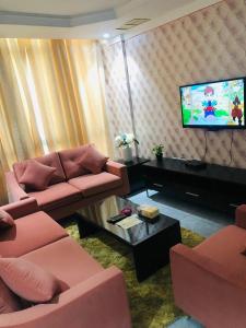 a living room with two pink couches and a television at شقق رهف السالميه in Kuwait