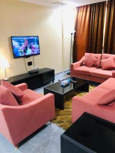a living room with pink furniture and a flat screen tv at شقق رهف السالميه in Kuwait