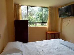 a bedroom with a bed and a large window at ROARI HOTEL in Trujillo
