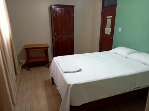 a bedroom with a white bed and a wooden cabinet at ROARI HOTEL in Trujillo