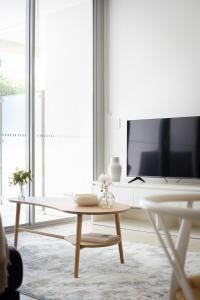 a living room with a table and a tv at The Alta Apartments by Urban Rest in Sydney