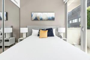 a bedroom with a large white bed with two lamps at The Alta Apartments by Urban Rest in Sydney