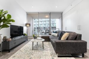 a living room with a couch and a tv and a table at The Alta Apartments by Urban Rest in Sydney