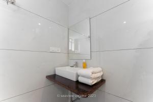 a white bathroom with a sink and a mirror at Sea View Holiday Vagator in Vagator