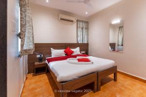 a bedroom with a large white bed with red pillows at Sea View Holiday Vagator in Vagator