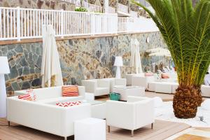 a patio with white couches and a palm tree at Hotel Altamadores in Puerto Rico de Gran Canaria