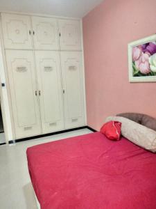 1 dormitorio con cama roja y armarios blancos en Real Apartments 399 - 3 quartos e 2 banheiros na quadra da Praia de Copacabana, en Río de Janeiro