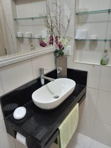um lavatório branco num balcão preto numa casa de banho em Real Apartments 399 - 3 quartos e 2 banheiros na quadra da Praia de Copacabana no Rio de Janeiro