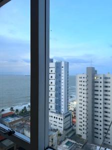 una ventana con vistas al océano y a los edificios en Flat number one temporadalitoranea, en São Luís