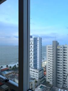 a view of the ocean and buildings from a window at Flat number one temporadalitoranea in São Luís