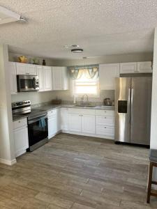 a kitchen with white cabinets and a stainless steel refrigerator at Very Private 3 Bed Home with HEATED Pool Palms and Big Fenced Yard in Pensacola