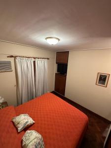 1 dormitorio con 1 cama con colcha de color naranja en Departamento temporario Maipú 700, Barrio Norte en San Miguel de Tucumán