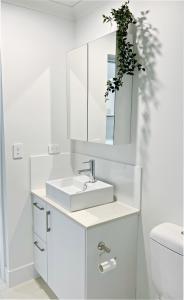 a white bathroom with a sink and a mirror at One on Harris Apartments in Wellington Point