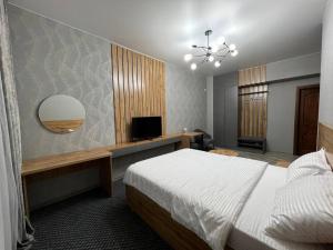 a bedroom with a bed and a flat screen tv at Rooms Hotel Semey in Semey