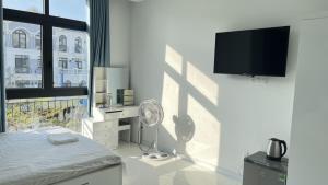 a white bedroom with a fan and a tv on a wall at Ngân Hà GrandWorld Phú Quốc in Phu Quoc