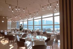 a restaurant with tables and chairs and a person in the background at Nina Hotel Tsuen Wan West in Hong Kong