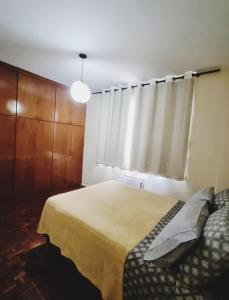 1 dormitorio con cama y ventana con cortina en Amplo e confortável. Ar condic, WiFi, TV. Metrô. Tijuca. en Río de Janeiro