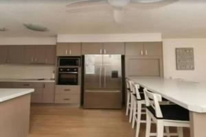 una cocina con electrodomésticos de acero inoxidable y encimeras blancas en Palm Breeze - Hosted by Burleigh Letting en Gold Coast