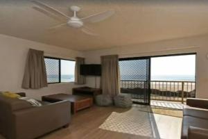 een woonkamer met een bank en een plafondventilator bij Palm Breeze - Hosted by Burleigh Letting in Gold Coast