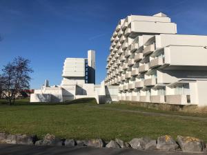 a white building with a tall building in the background at Studio Bee Home in De Haan