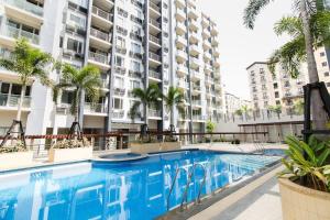 a swimming pool with palm trees in front of a building at 2 BR Condo Apartment near NAIA 3 Pasay City in Manila