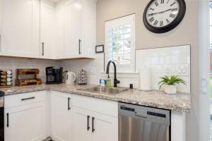 a kitchen with white cabinets and a clock on the wall at Montara Beach Mountain Escape in Montara
