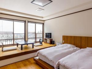 1 dormitorio con cama, mesa y ventanas en kamosu mori en Tokamachi