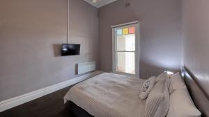 a bedroom with a bed and a tv and a window at Commercial Hotel Lockhart in Lockhart