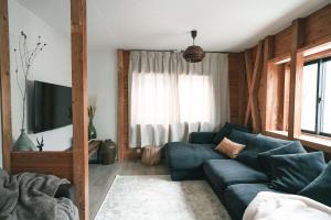 ein Wohnzimmer mit einem blauen Sofa vor einem Fenster in der Unterkunft Sugi Chalet in Myōkō